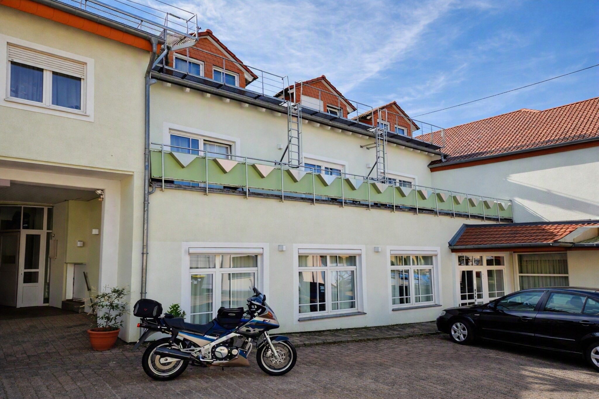 En toetagers bygning med en motorcykel parkeret i indkørslen.