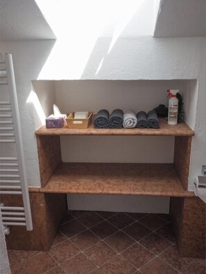 Un bagno con un portasciugamani pieno di asciugamani arrotolati, una scatola di fazzoletti e una bottiglia di disinfettante per le mani.