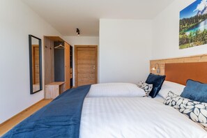A bedroom with two beds, a wooden wardrobe, a hanging wardrobe, and a painting on the wall. - Chalet right next to the ski area (St. Lambrecht)