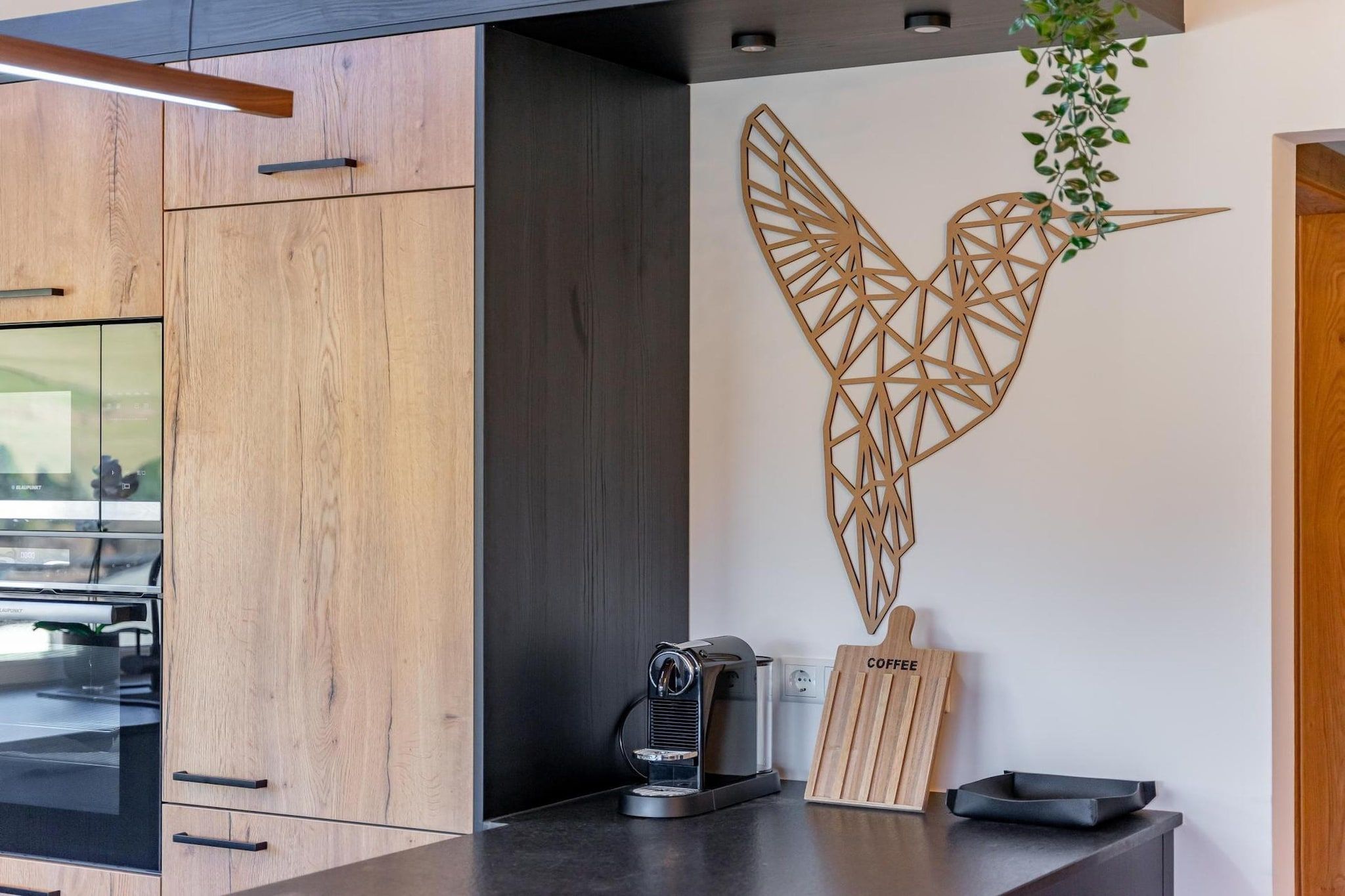 Une cuisine moderne avec des meubles en bois, une machine à café et un élément décoratif mural.