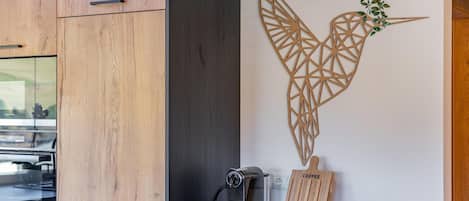 A modern kitchen with wooden cabinets, a coffee machine, and a decorative wall piece.