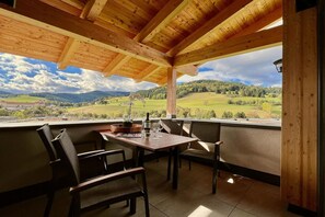 Un espace extérieur abrité, avec une table et des chaises, offrant une vue sur un paysage pittoresque.