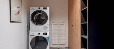 A laundry room with two stacked washing machines and a drying rack.