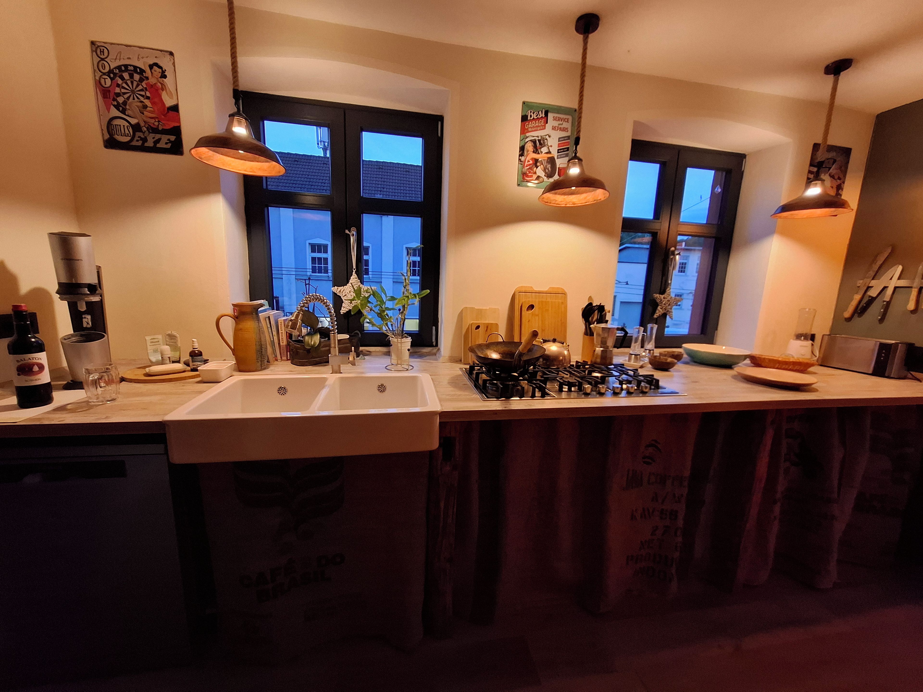 Eine Küche mit Spüle, Herd, Pendelleuchten und diversen Küchengeräten.