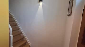 Eine Treppe mit Schachbrettmuster, einer weißen Wand und einer Leuchte.