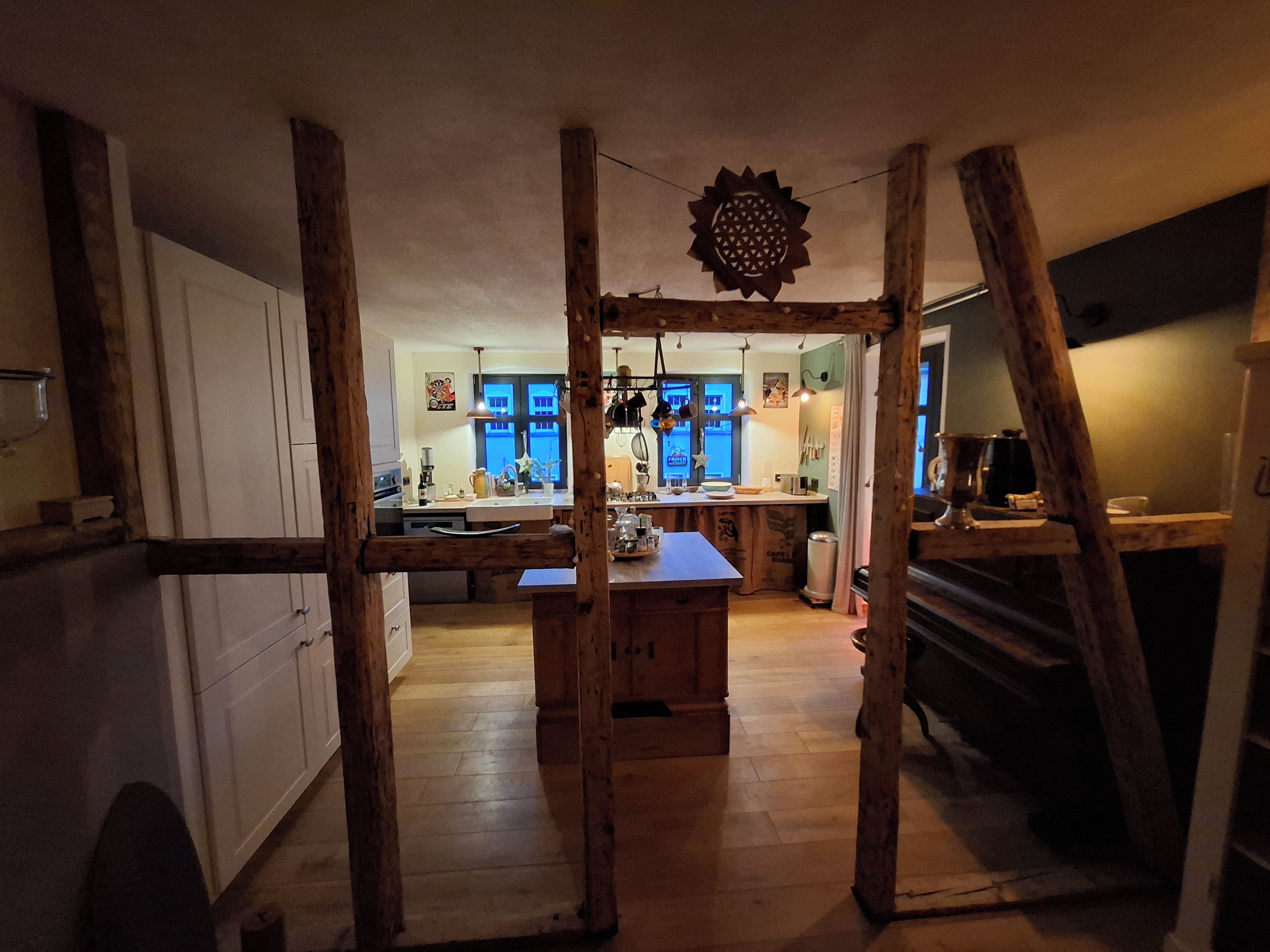 Eine rustikale Küche mit Holzbalken, einer zentralen Kochinsel und Blick in den Essbereich.