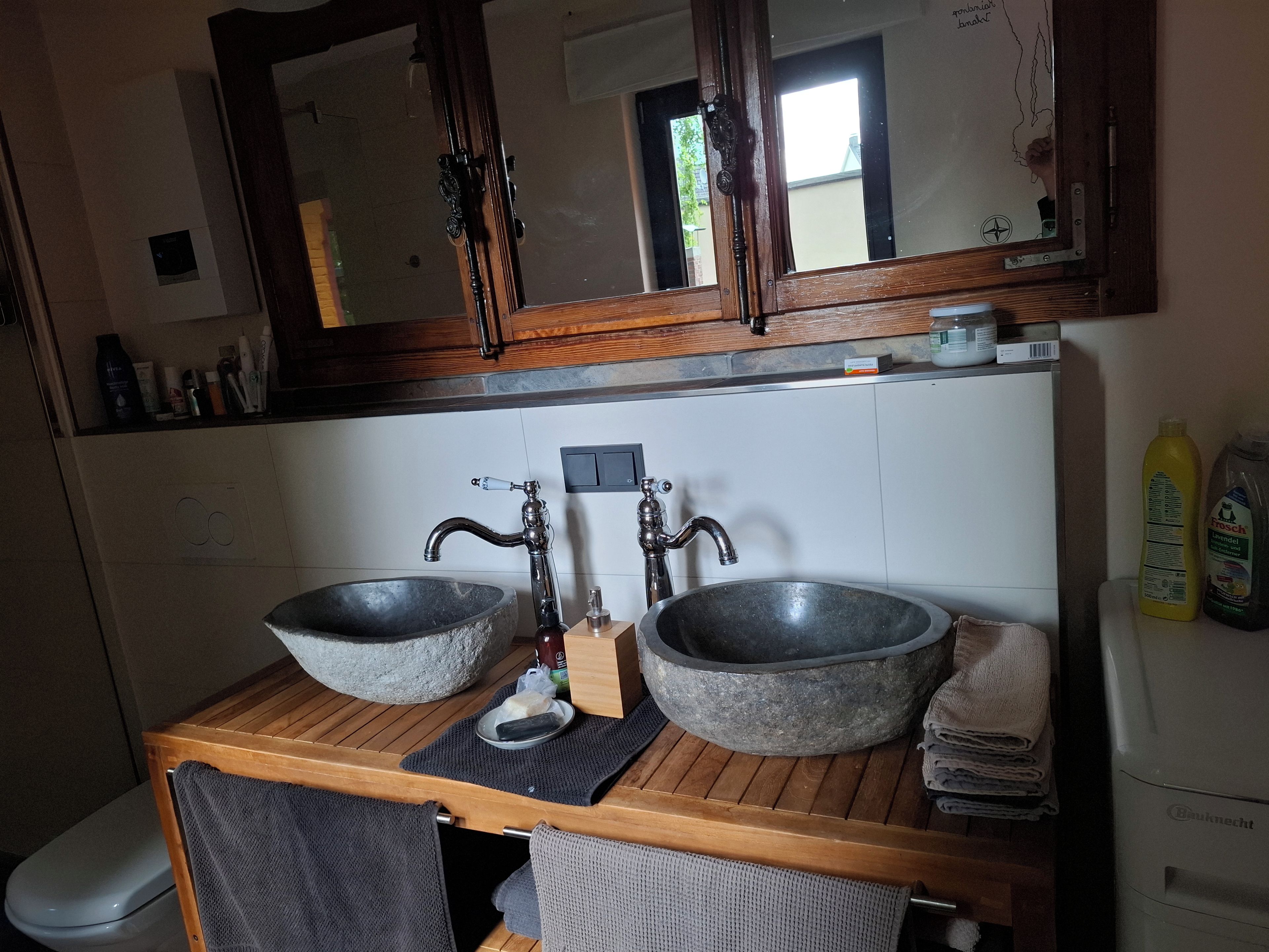 Un baño con dos lavamanos de piedra, tocador de madera y un espejo sobre el lavabo.