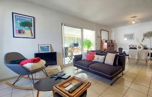 Ein Wohnzimmer mit einer Couch, einem Schaukelstuhl, einem Couchtisch und einem Fernseher.