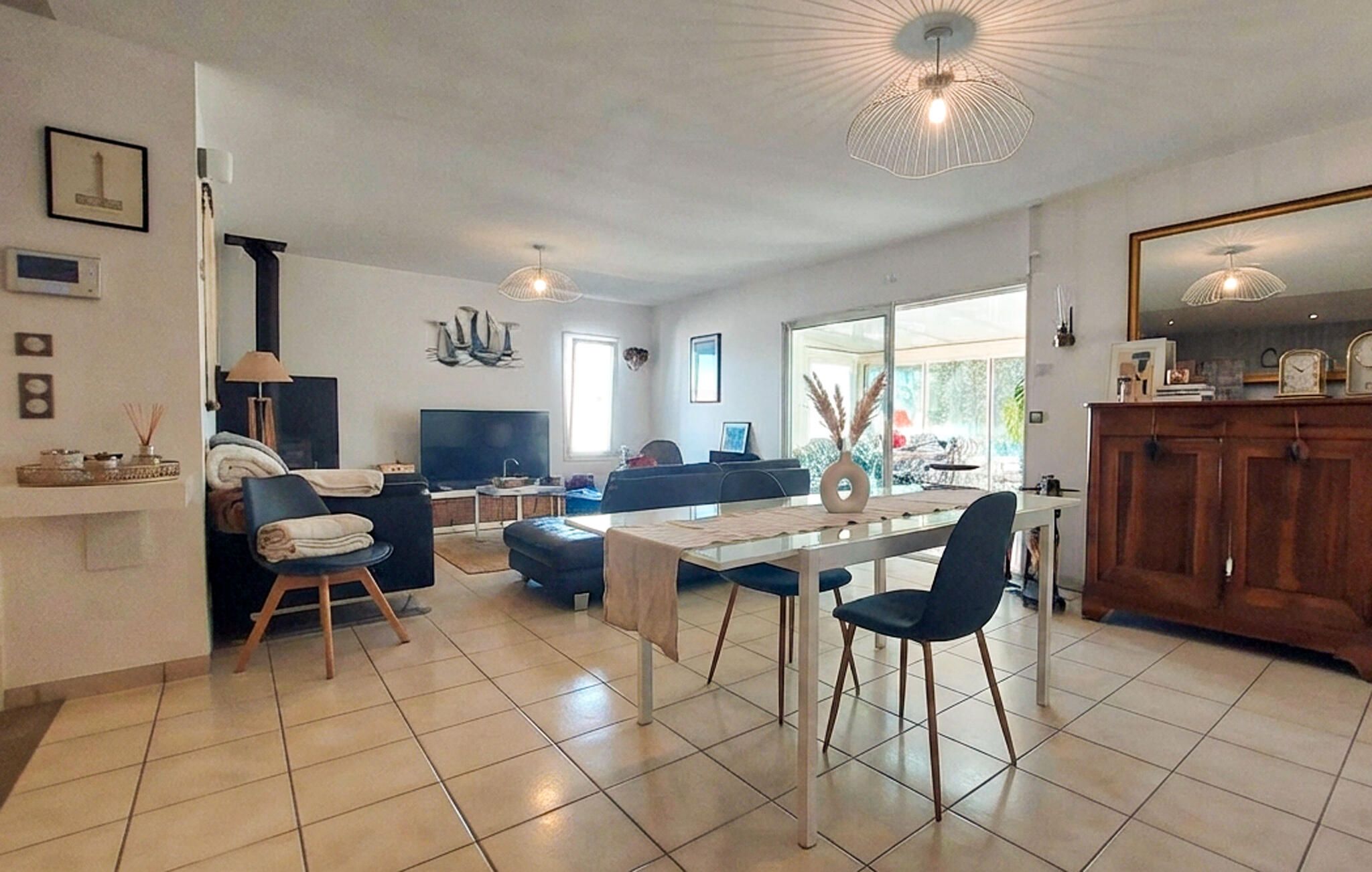 A modern living room with a dining area, a TV, and a large window.
