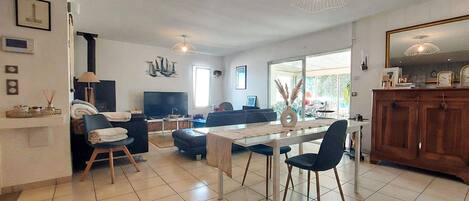 A modern living room with a dining area, a TV, and a large window.