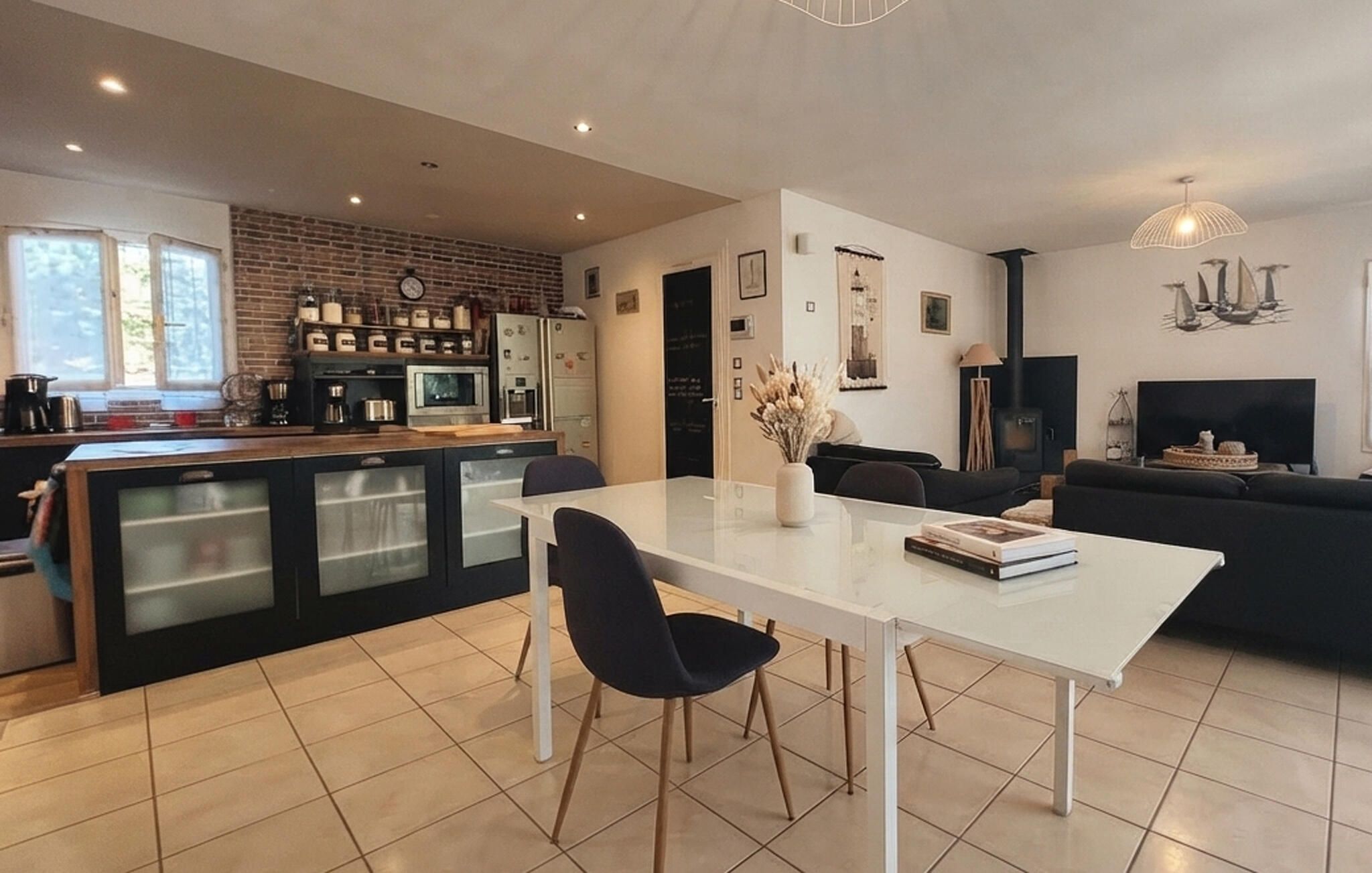 Een moderne keuken met een eetgedeelte, een zwarte bank en een televisie in een woonkamer.
