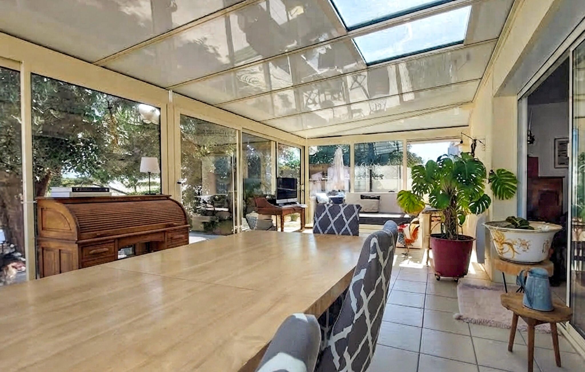 A spacious room with a large wooden table, a comfortable sofa, and a TV.