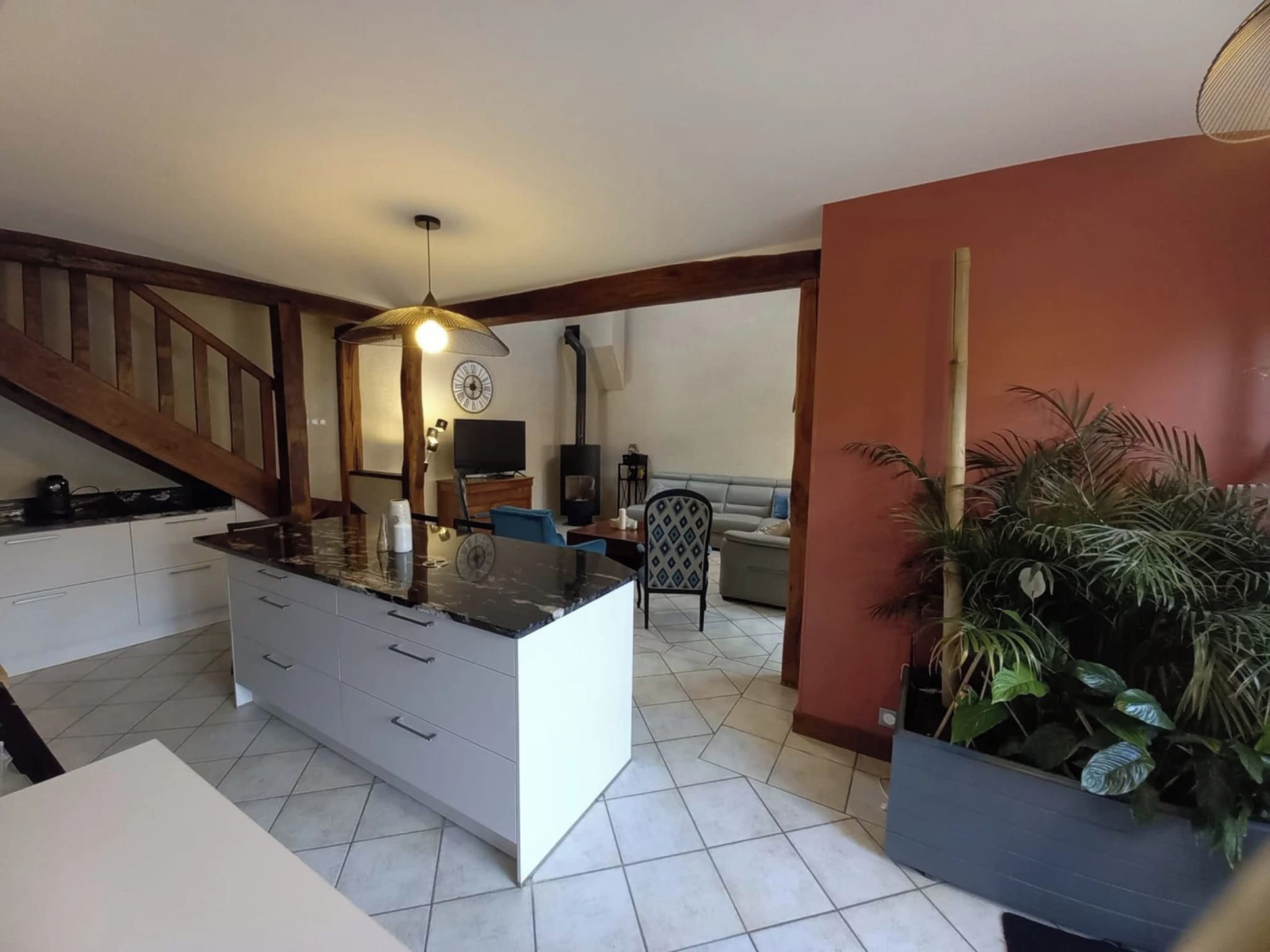 Une cuisine moderne avec un îlot central, un coin repas avec un canapé et un escalier.