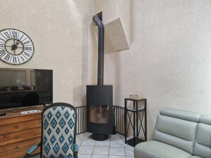 A living room with a fireplace, a clock, a TV, and a sofa.