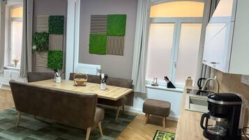 Un comedor moderno con una mesa de madera, sillas tapizadas en tonos marrones y un tapete estampado verde.