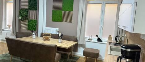 A modern dining area with a wooden table, brown upholstered chairs, and a green patterned rug.