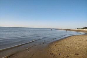 A beach with a clear sky, calm water, and a few people walking. - Holiday apartment with 2 bedrooms (Cuxhaven\/Sahlenburg)