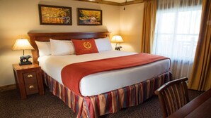 A hotel room with a large bed, two bedside lamps, a wooden nightstand with a drawer, a small statue, and two framed pictures on the wall. - 1BR at Westgate Smoky Mountain – Views, Spa & Water Park Fun (Gatlinburg)
