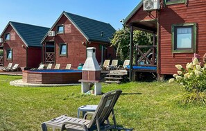 A rustic cabin with a chimney, outdoor seating, and a pool. - Nice home in Rusinowo with outdoor swimming pool (Rusinowo)