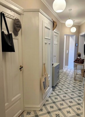 Un pasillo con baldosas de diseño, puertas blancas y bolsas colgando.