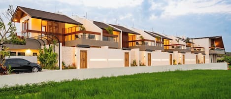 Un edificio residencial moderno de varios pisos con techo plano, ventanas grandes y un césped bien cuidado.