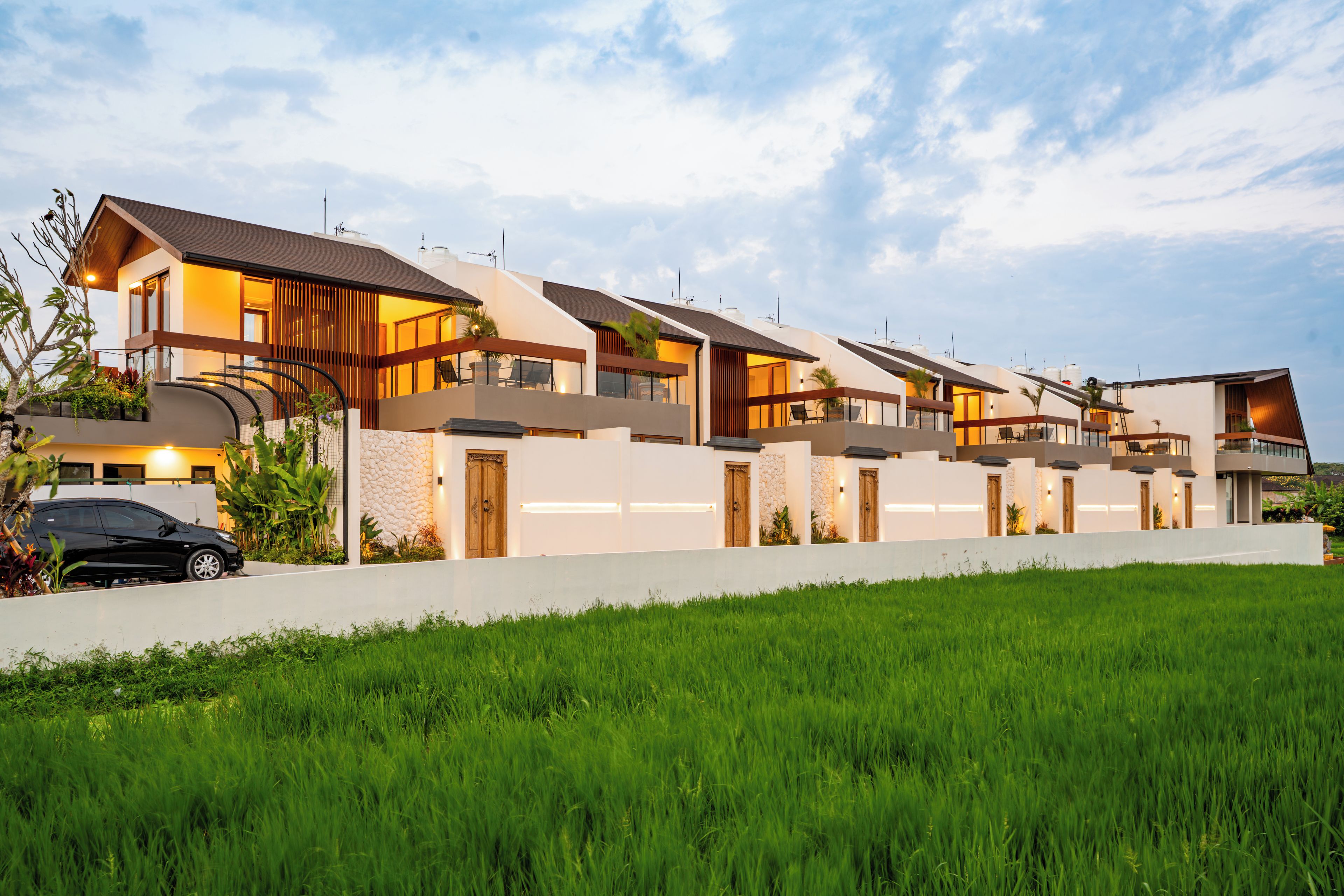 A modern residential building with multiple levels, large windows, and a well-maintained lawn.