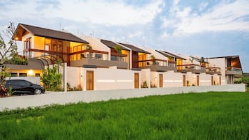 A modern residential building with multiple levels, large windows, and a well-maintained lawn.
