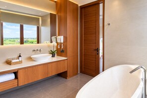A modern bathroom with a freestanding bathtub, a large mirror, and a vanity with a sink and towel rack. - Elysera Villa Nyanyi (Tabanan)