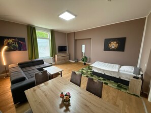A modern living room with a sofa, a dining table, and a bed. - Apartment '2' with Wi-Fi (Erfurt)