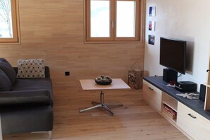 A compact living space with a sofa, a small table with a decorative item, a television, and a cabinet with drawers. - Holiday apartment Bernau Dorf (Bernau)