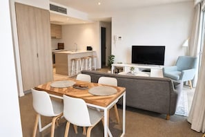 Ein modernes Wohnzimmer mit einer Couch, einem Fernseher und einem Essbereich mit Stühlen und einem Tisch.