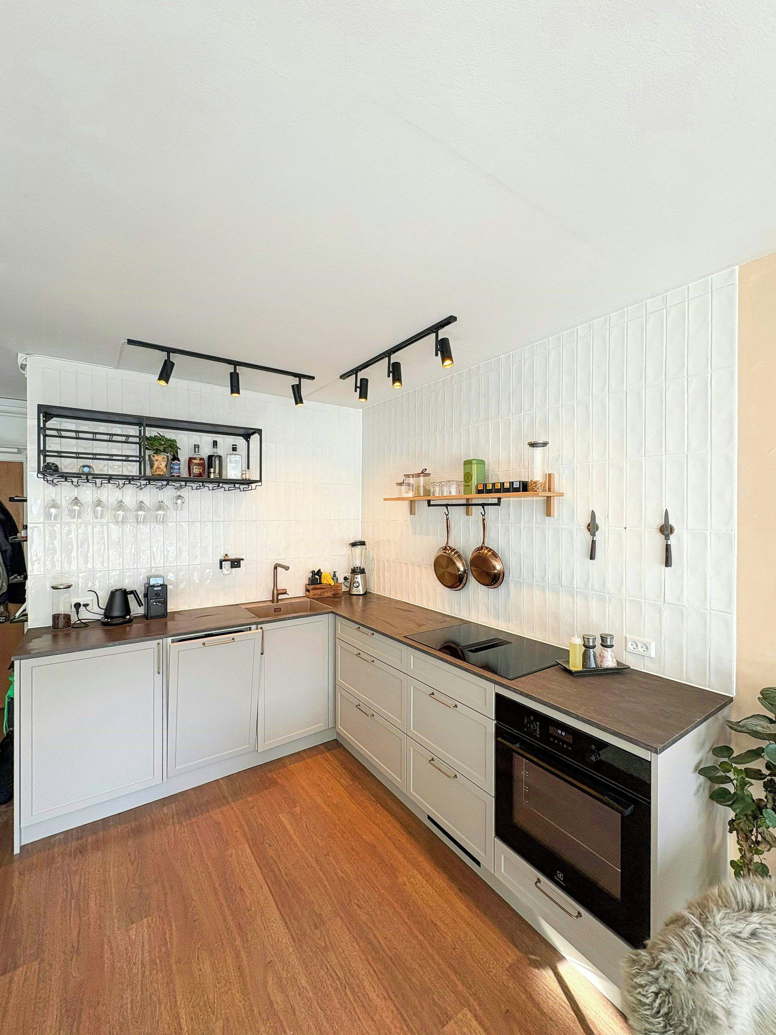 Une cuisine moderne avec des meubles blancs, un plan de travail en bois et un four encastré.