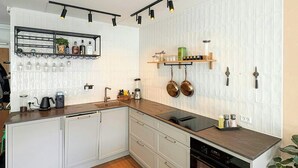 A modern kitchen with white cabinetry, a wooden countertop, and a built-in oven. - Light and spacious flat with balcony in Copenhagen (København S)