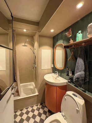 A bathroom with a shower, sink, toilet, and a mirror. - Light and spacious flat with balcony in Copenhagen (København S)