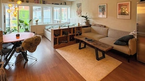 A cozy living room with a sofa, a coffee table, and a dining area with chairs and a table. - Light and spacious flat with balcony in Copenhagen (København S)
