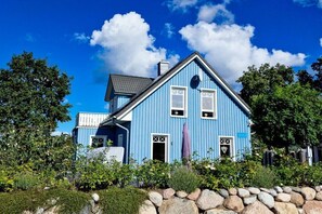 A blue house with a stone wall in front, surrounded by greenery. - Holiday home in Bodstedt with swimming pool (Bodstedt)