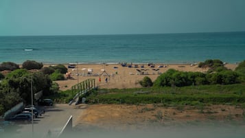 Uma praia com barcos, guarda-sóis e um estacionamento.
