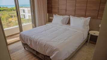 Quarto de hotel com uma cama grande, mesa de cabeceira e vista para o oceano.