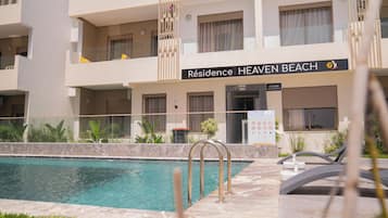 Um hotel chamado 'Residence Heaven Beach' com piscina, área de estar externa e recepção.