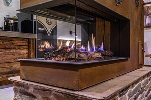 Ein Kamin aus Stein mit Glaseinsatz, eine Holzvertäfelung und eine Metalldür.