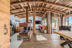 A rustic interior with a wooden ceiling, a fireplace, and a stone fireplace surround. - Mountain chalet UNIQUE (Schöfweg -Langfurth)