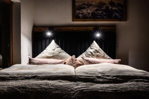 A bed with a headboard featuring two triangular designs and a pair of lights. - Mountain chalet UNIQUE (Schöfweg -Langfurth)