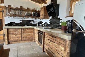 A kitchen with wooden cabinetry, a black countertop, and a built-in oven. - Mountain chalet UNIQUE (Schöfweg -Langfurth)