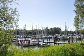 A marina with multiple boats docked at wooden piers, surrounded by greenery. - Holiday apartment with 2 bedrooms (Wangerland)