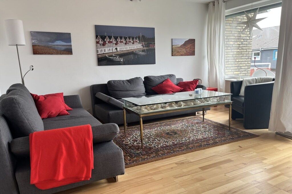 A living room with a sofa, a glass coffee table, and a patterned rug.
