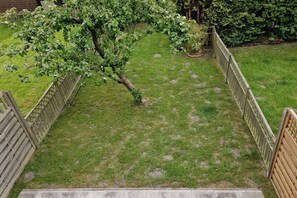 Een gazon met een houten omheining en een boom.