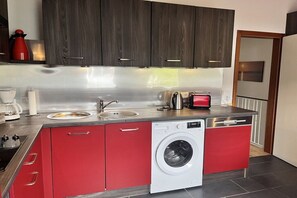 Een kleine keuken met een wasmachine, een broodrooster en een koffiezetapparaat.