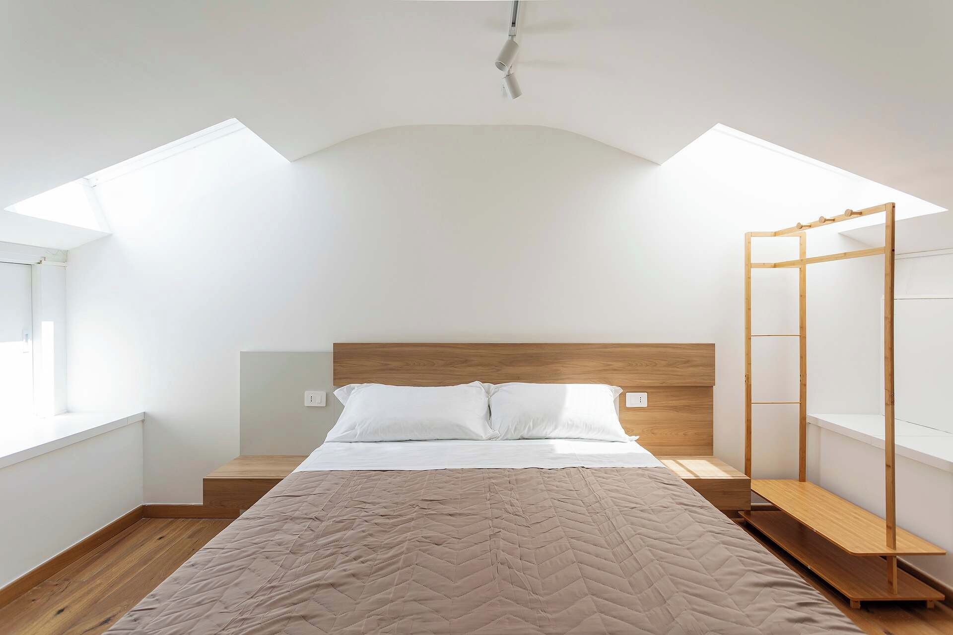 Una camera da letto con un letto, una testiera in legno e un lucernario.