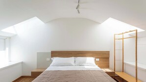Ein Schlafzimmer mit einem Bett, einem Holz-Kopfteil und einem Dachfenster.