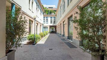 Un stretto corridoio lastricato fiancheggiato da edifici, alberi e lampioni.